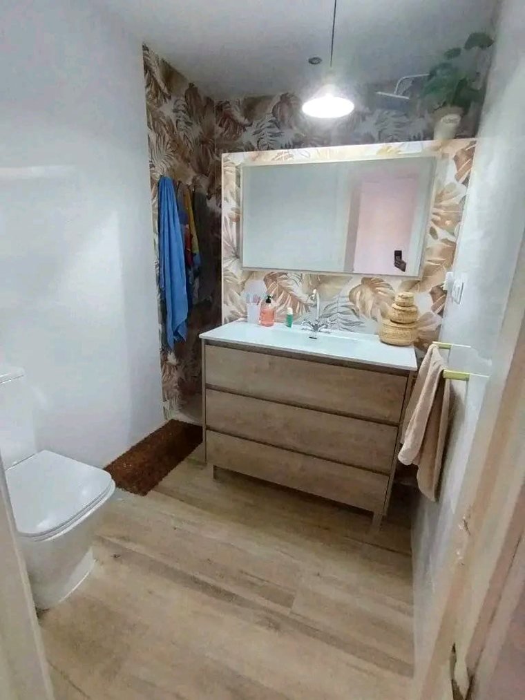 Baño reformado con suelo de madera y mueble a juego